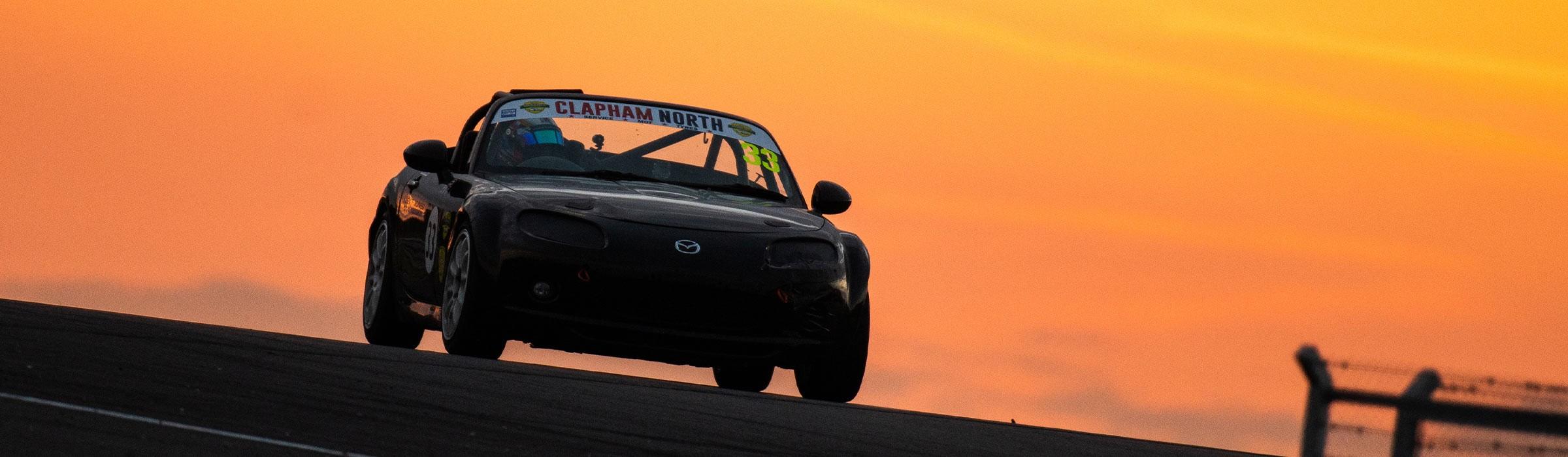 Alex driving his mazda in front of a gorgeous orange sunset horizon!